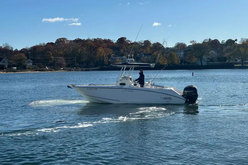 Slide: The Image of 2006 Boston Whaler 240 Outrage boat cruising on a calm lake with autumn trees in the background. - 4