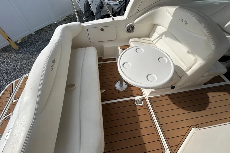 Slide: The Image of 2004 Sea Ray 280 Sundancer interior with white seating and round table on teak deck. - 10