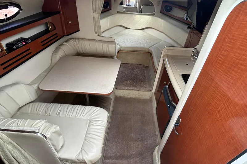 Slide: The Image of 2004 Sea Ray 280 Sundancer cabin interior with seating, table, and kitchenette. - 24