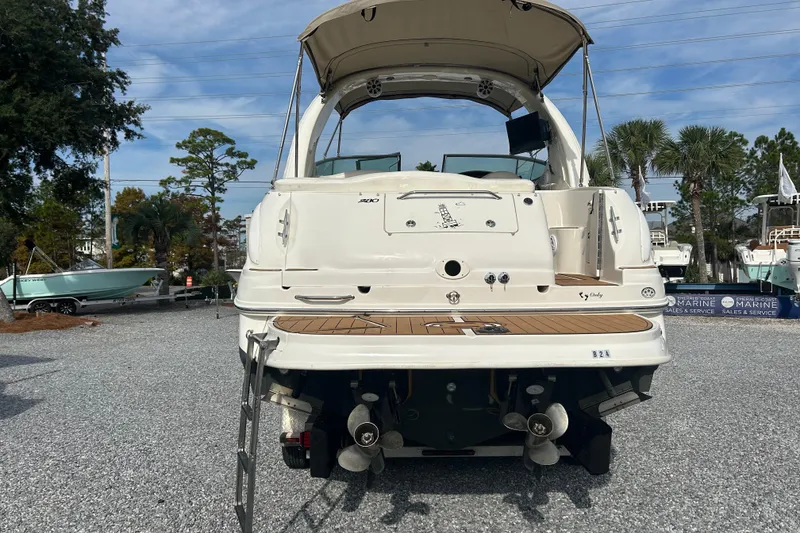 Slide: The Image of 2004 Sea Ray 280 Sundancer boat, rear view, parked on gravel with trees in background. - 3