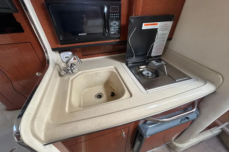 Slide: The Image of 2004 Sea Ray 280 Sundancer galley with sink, stove, and microwave. - 31