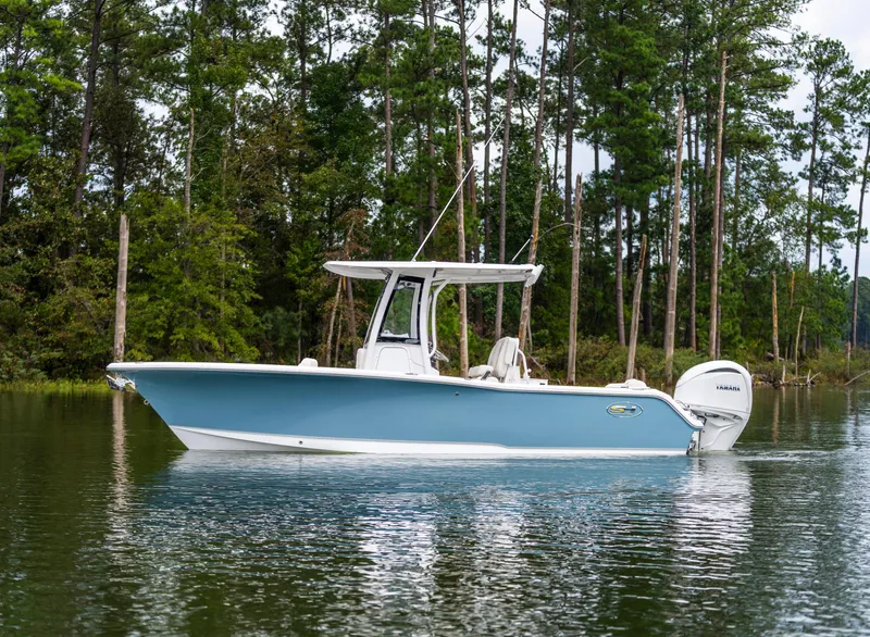 Slide: The Image of 2026 Sea Hunt Ultra 245 SE boat on calm water, surrounded by lush trees. - 9