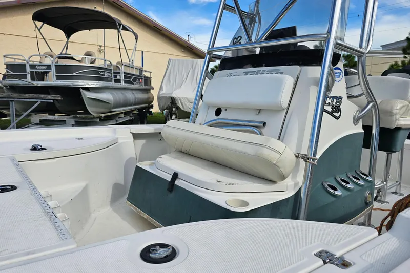 Slide: The Image of 2006 Triton 220 LTS boat interior with seating and console, parked near a pontoon boat. - 14