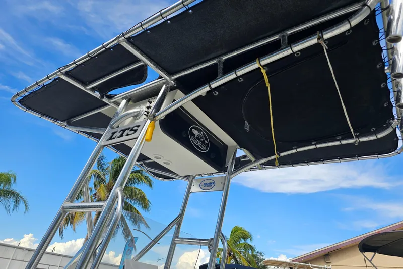 Slide: The Image of 2006 Triton 220 LTS boat with T-top, palm trees in background, clear sky. - 18