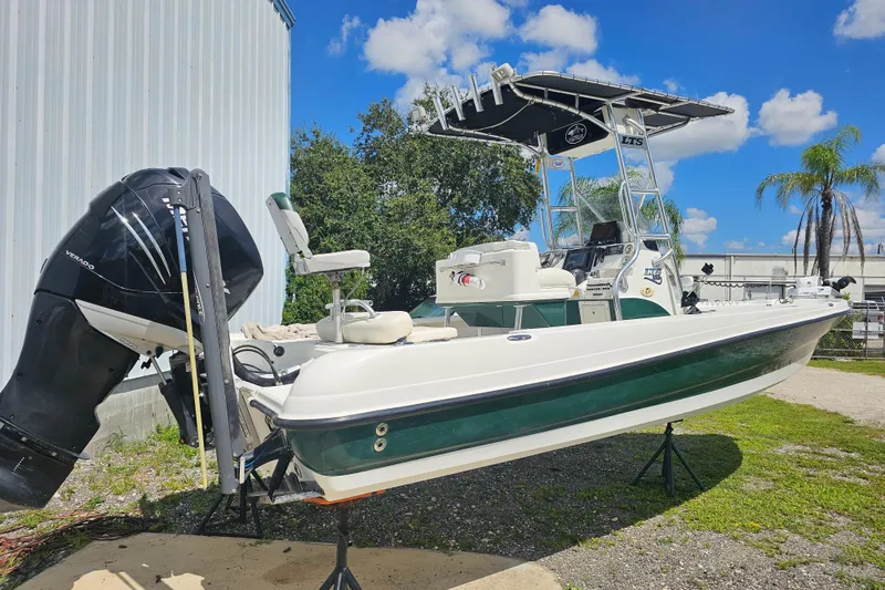Slide: The Image of 2006 Triton 220 LTS boat with outboard motor, parked outdoors under blue sky. - 22
