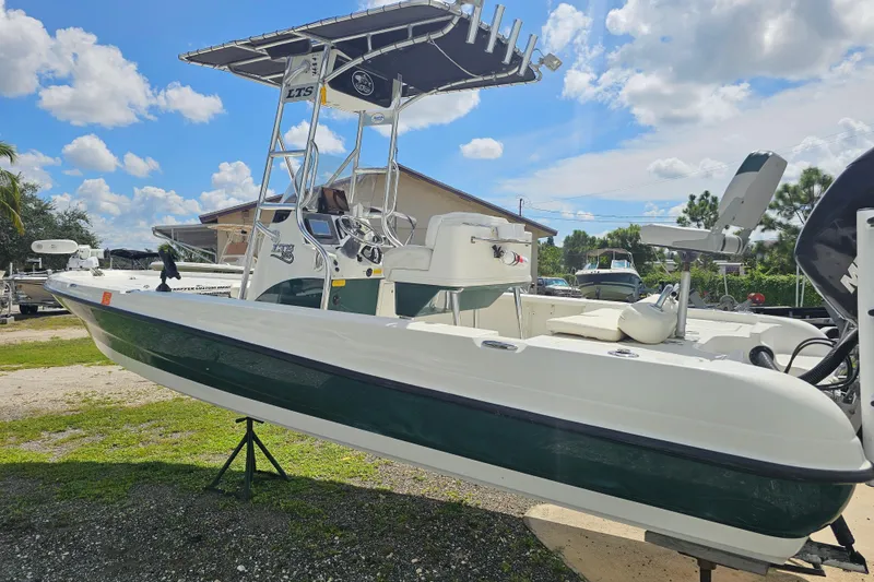 Slide: The Image of 2006 Triton 220 LTS boat with T-top, parked outdoors under a blue sky. - 27