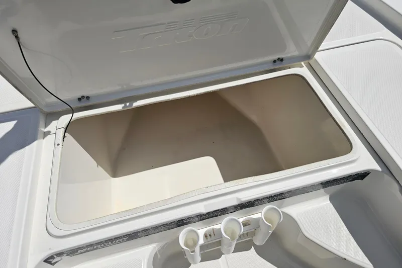 Slide: The Image of Open storage compartment on a 2006 Triton 220 LTS boat, featuring rod holders. - 32