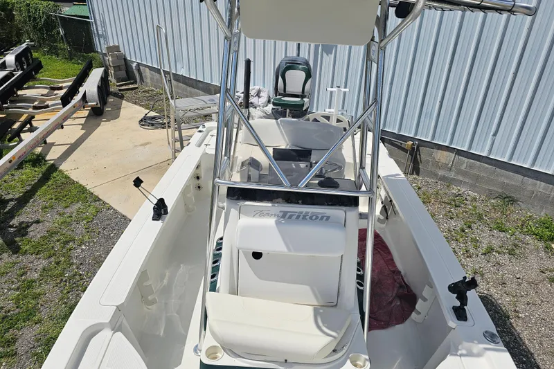 Slide: The Image of 2006 Triton 220 LTS boat with T-top, parked outdoors near a metal building. - 34
