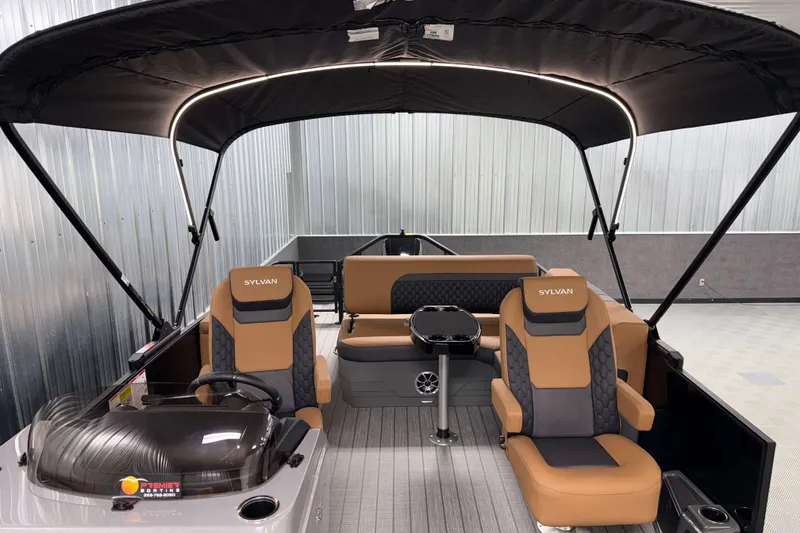 Slide: The Image of 2026 Sylvan L3 CLZ DH boat interior with tan and black seating, under a canopy. - 16