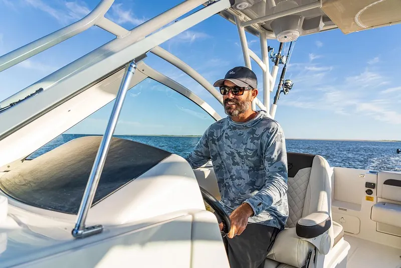 Slide: The Image of Manufacturer Provided Image: Man piloting 2026 Sailfish 245 DC boat on open water, under clear blue sky. - 6