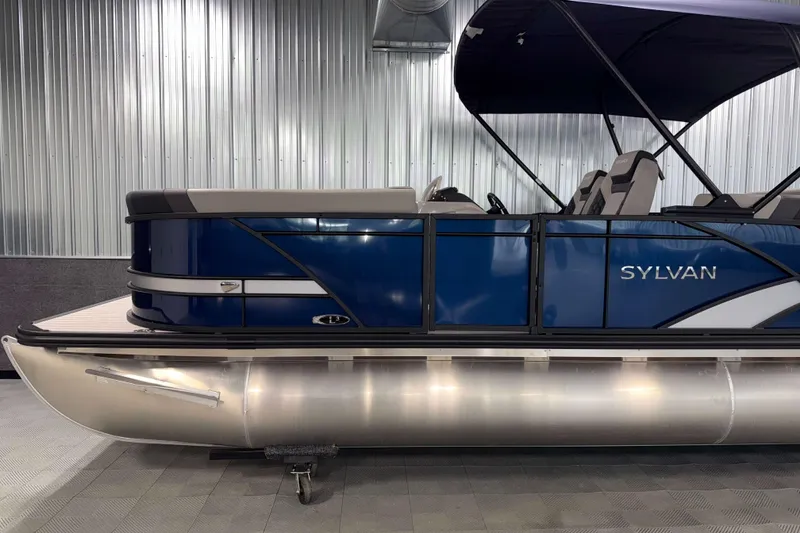 Slide: The Image of 2026 Sylvan L3 CLZ DH pontoon boat with blue exterior and canopy in a showroom. - 21