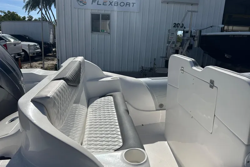 Slide: The Image of Interior of a 2024 Caribe DL-20S boat with white seating and Flexboat facility background. - 5