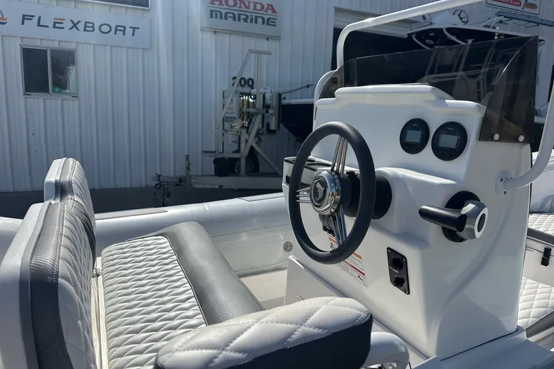 Slide: The Image of 2024 Caribe DL-20S boat console with steering wheel and gauges, near Flexboat and Honda Marine signs. - 6
