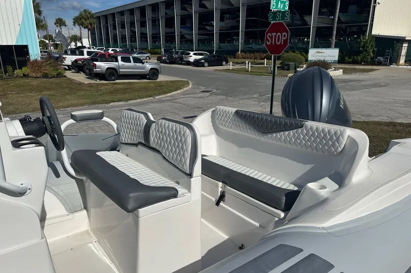Slide: The Image of 2024 Caribe DL-20S boat interior with gray seating, parked near a marina. - 9