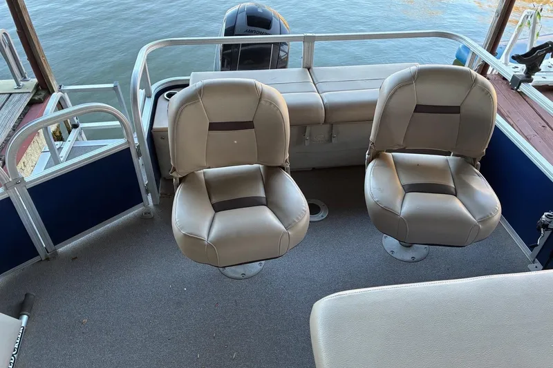 Slide: The Image of 2017 Sun Tracker Fishin' Barge 22 DLX interior with two beige seats and water view. - 6