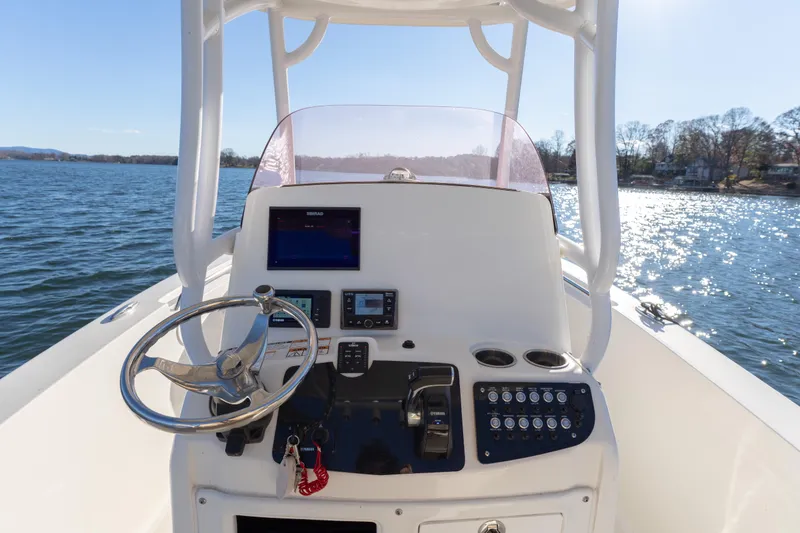 Slide: The Image of 2020 NauticStar 2602 Legacy boat helm with steering wheel and controls on water. - 7