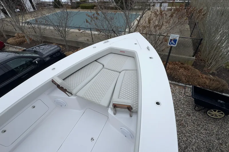 Slide: The Image of 2024 Jupiter 32 FS boat with cushioned seating, parked near a pool and reserved parking sign. - 49