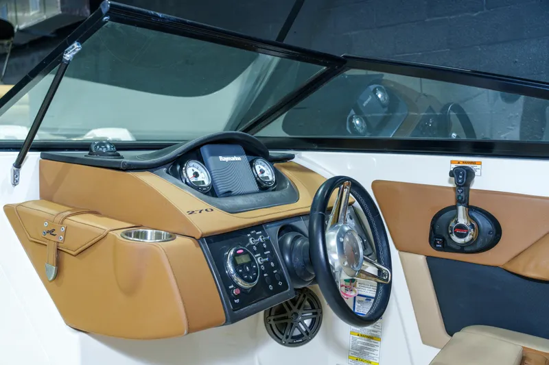 Slide: The Image of 2015 Sea Ray 270 Sundeck dashboard with steering wheel and control panel. - 14