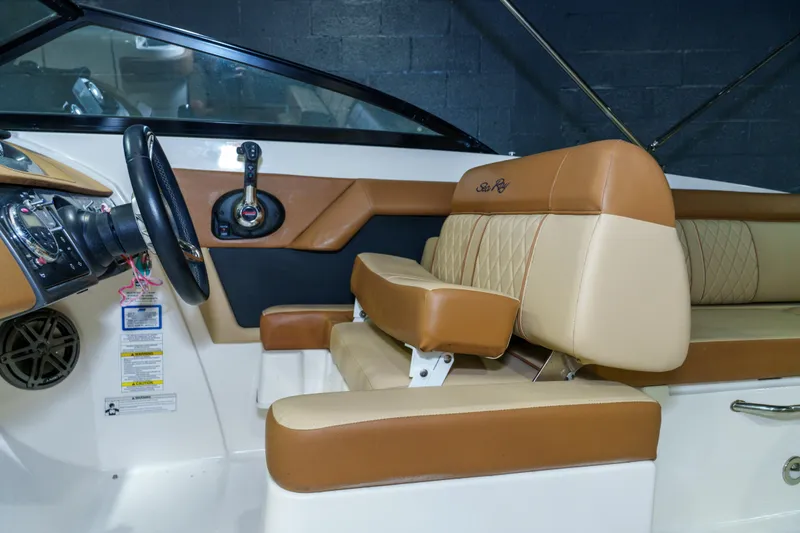 Slide: The Image of 2015 Sea Ray 270 Sundeck interior with tan and brown seating, steering wheel, and controls. - 16