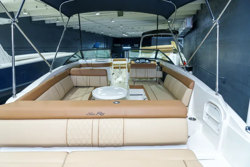 Slide: The Image of 2015 Sea Ray 270 Sundeck interior with tan seating and canopy in showroom. - 22
