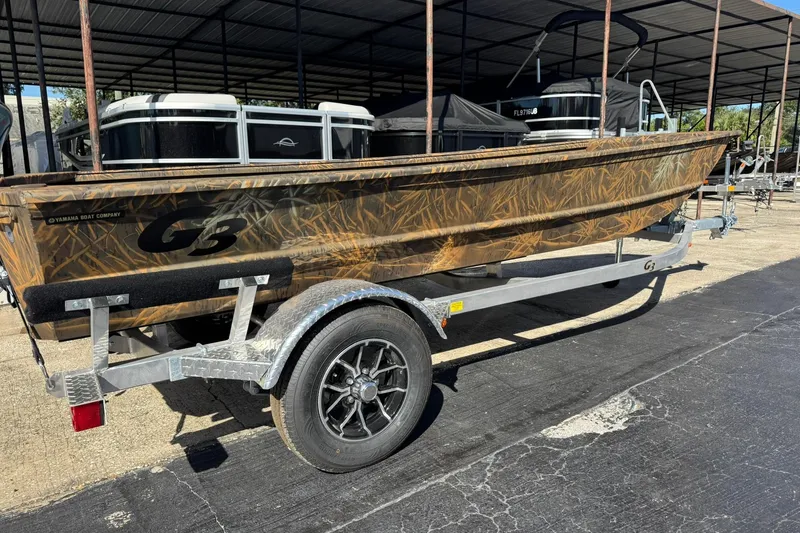 The Image of 2026 G3 Gator Tough 15 DK boat on trailer, camo design, parked outdoors. - 0