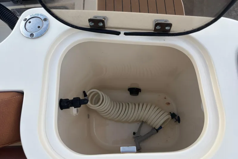 Slide: The Image of Open storage compartment on 2017 Scout 255 Dorado boat with coiled hose inside. - 11