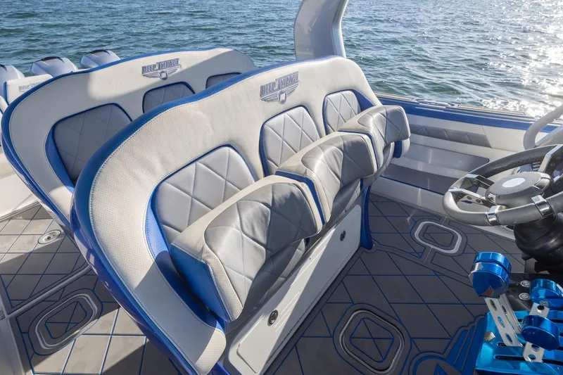 Slide: The Image of 2019 Deep Impact 399 Sport boat interior with blue and gray seating, steering wheel, and ocean view. - 22