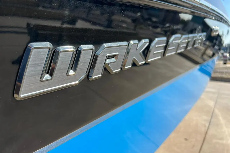 Slide: The Image of 2019 Malibu Wakesetter 24 MXZ boat logo on sleek black and blue hull. - 14