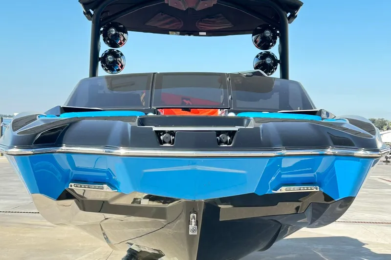 Slide: The Image of 2019 Malibu Wakesetter 24 MXZ boat, blue and black, docked under clear sky. - 9