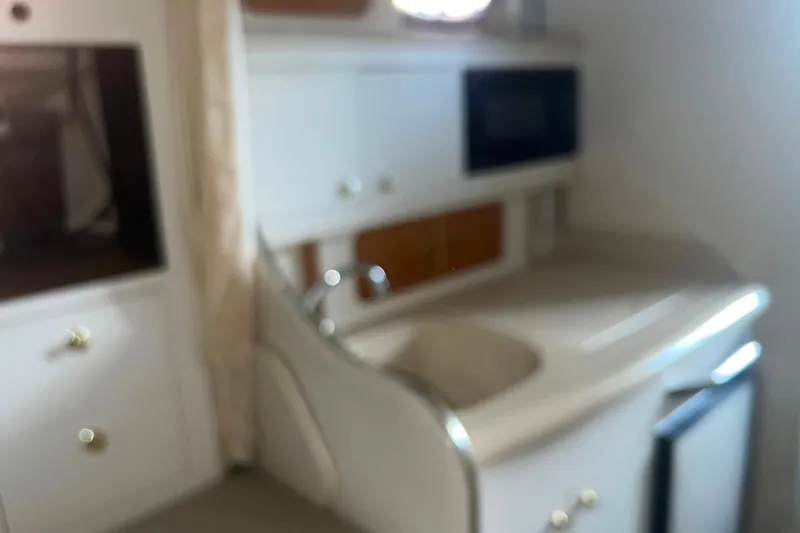 Slide: The Image of 1999 Sea Ray 290 Sundancer interior kitchen with sink, cabinets, and appliances. - 24