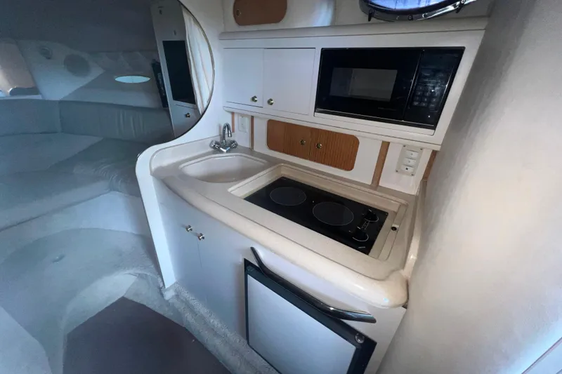 Slide: The Image of 1999 Sea Ray 290 Sundancer interior with kitchenette, sink, stove, and microwave. - 25