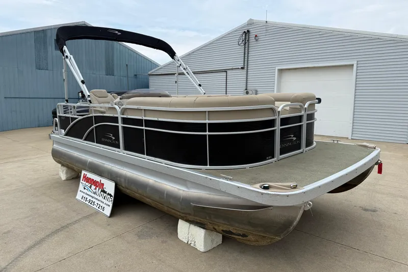 Slide: The Image of 2015 Bennington 18 SLX pontoon boat with beige seating, displayed outdoors. - 6