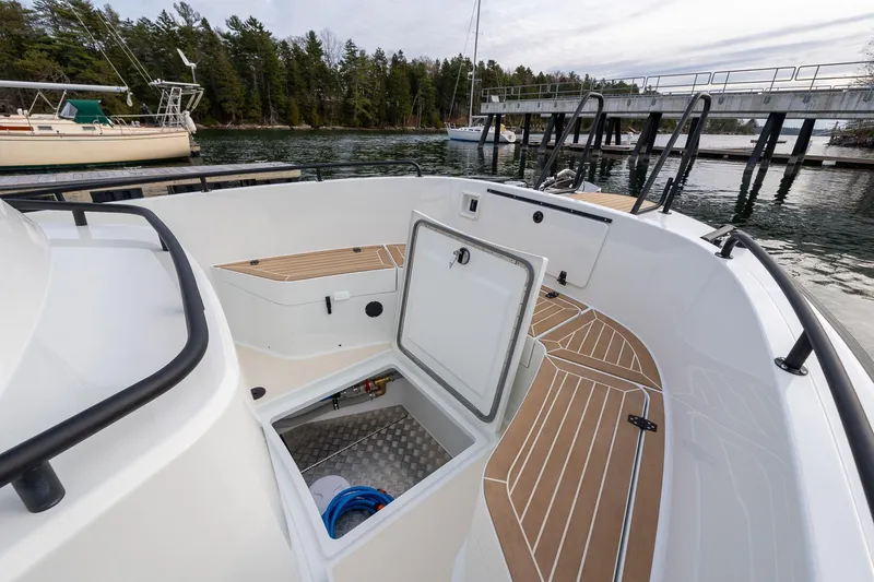 Slide: The Image of 2026 Targa 27.2 boat deck with open storage hatch, docked near a scenic shoreline. - 9