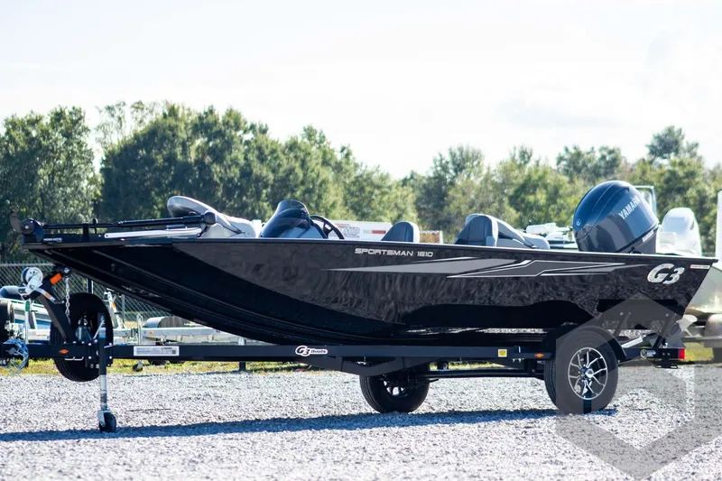 The Image of 2026 G3 Sportsman 1610 boat on trailer, parked outdoors with trees in background. - 1