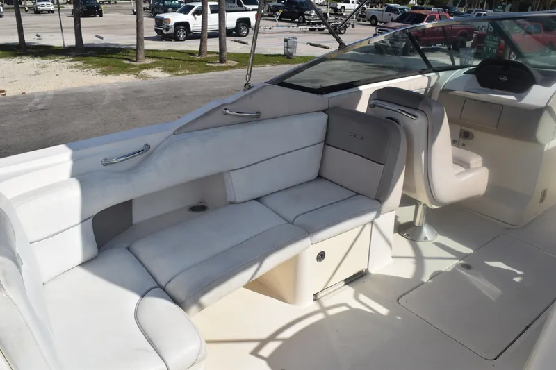 Slide: The Image of 2005 Sea Ray SLX 280 boat interior with beige seating and dashboard, parked outdoors. - 28