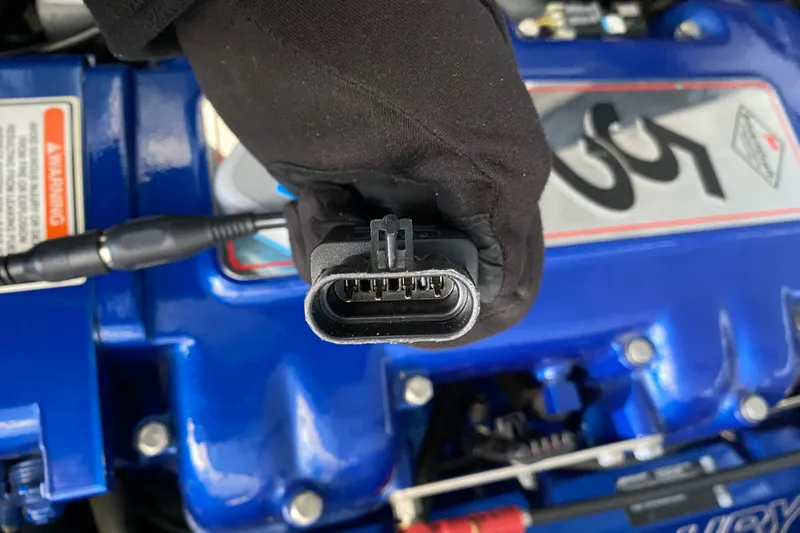 Slide: The Image of Close-up of a connector held over a blue engine cover, Formula 400 Super Sport 2006. - 17