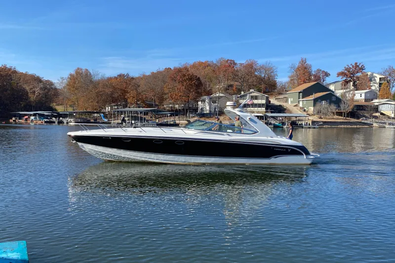 The Image of 2006 Formula 400 Super Sport boat cruising on a scenic lake with autumn trees. - 3