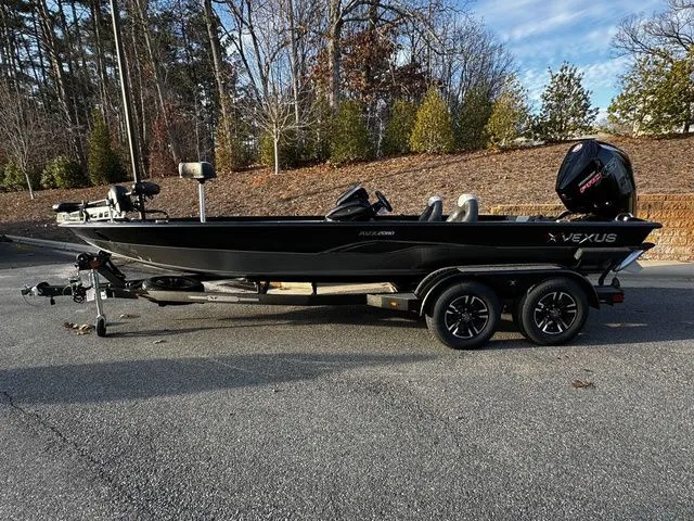 The Image of 2024 Vexus AVX2080 boat on trailer, parked outdoors, surrounded by trees and clear sky. - 1