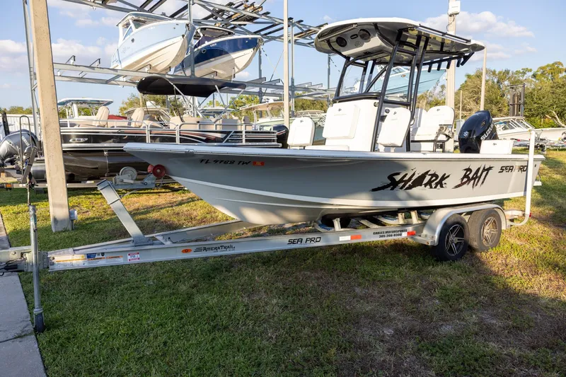 Slide: The Image of 2024 Sea Pro 210 Bay boat on trailer, labeled "Shark Bait," in a marina setting. - 1