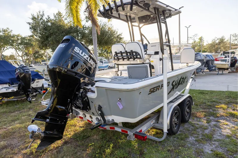 Slide: The Image of 2024 Sea Pro 210 Bay boat with Suzuki engine on trailer, parked outdoors. - 2