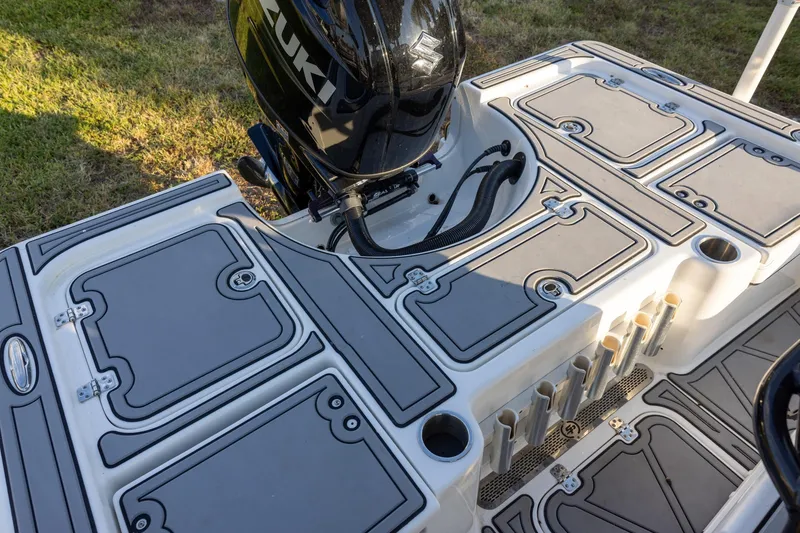 Slide: The Image of 2024 Sea Pro 210 Bay boat deck with Suzuki engine, featuring storage compartments and rod holders. - 6