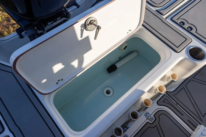 Slide: The Image of Open storage compartment on 2024 Sea Pro 210 Bay boat, featuring rod holders and cup holder. - 8