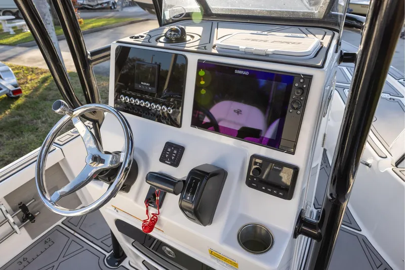 Slide: The Image of 2024 Sea Pro 210 Bay boat dashboard with steering wheel and navigation controls. - 9