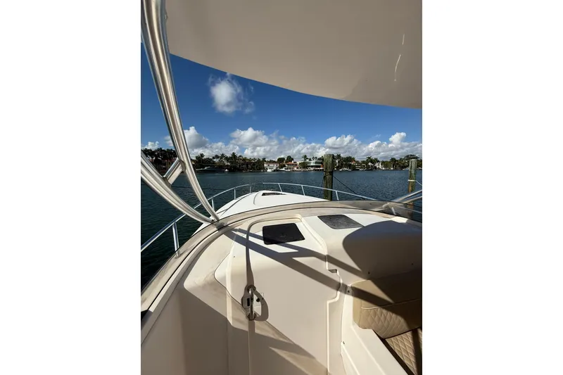 Slide: The Image of 2008 Intrepid 370 Cuddy boat interior with seating and railing, docked near palm trees. - 37