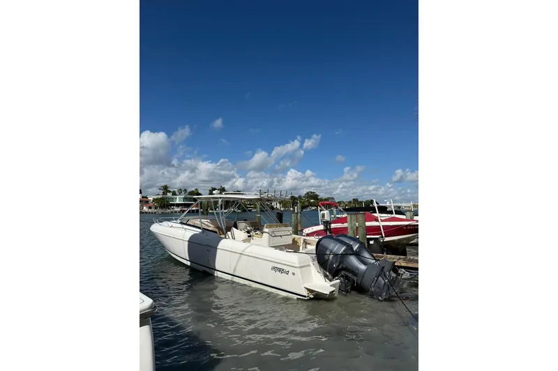 Slide: The Image of 2008 Intrepid 370 Cuddy boat docked, featuring dual outboard engines and sleek design. - 6