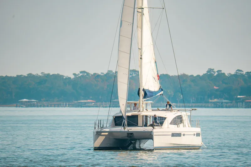 Slide: The Image of Sailing catamaran Leopard 48, 2016 model, cruising on calm waters near a forested shoreline. - 116