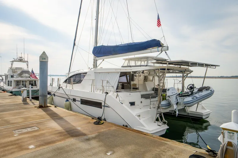 Slide: The Image of 2016 Leopard 48 yacht docked with dinghy, featuring sleek design and American flag. - 21
