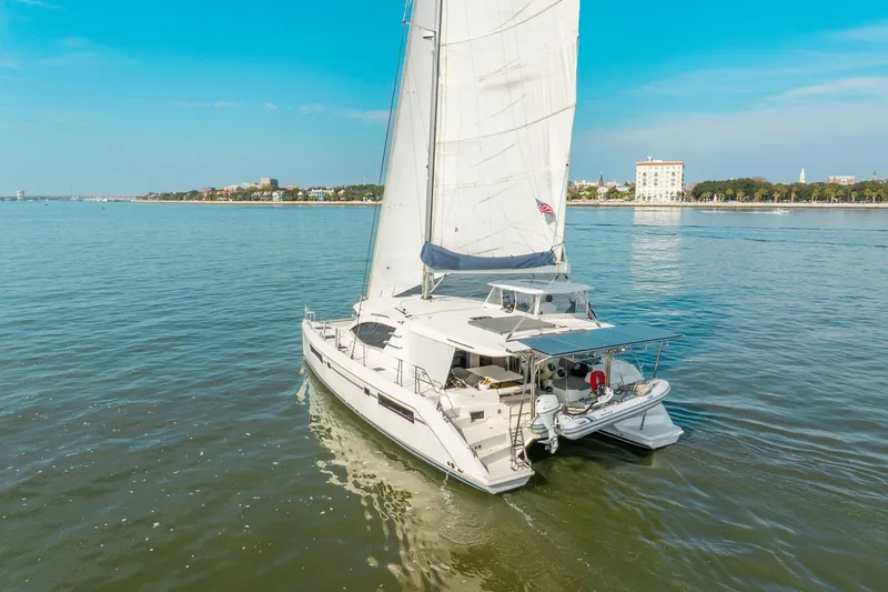 Slide: The Image of 2016 Leopard 48 yacht sailing near a coastal city under clear blue skies. - 8