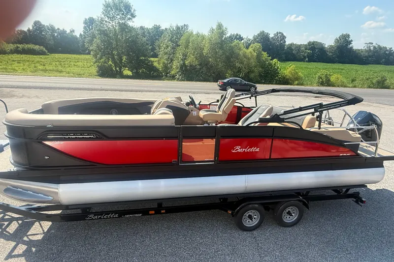 Slide: The Image of 2026 Barletta Cabrio 24UC pontoon boat on trailer, red and black design, parked outdoors. - 32