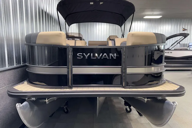 Slide: The Image of 2026 Sylvan L3 DLZ pontoon boat in showroom, featuring sleek black design and beige seating. - 23